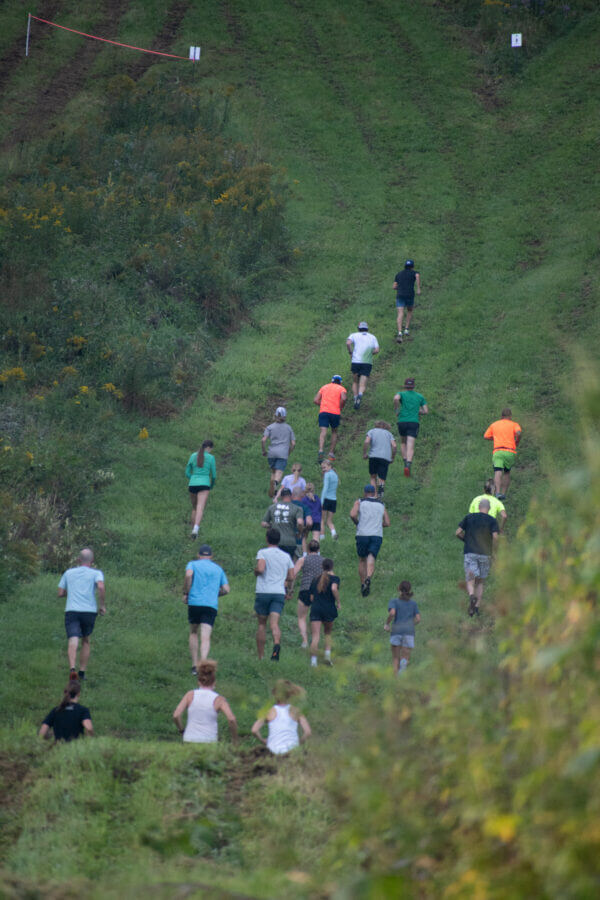 group of runners running up a steep grassy trail