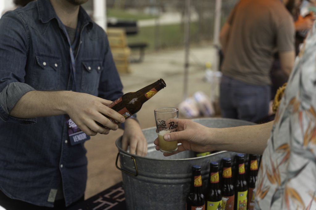 Man pouring beer into a tasting glass at beer, wine and cheese festival