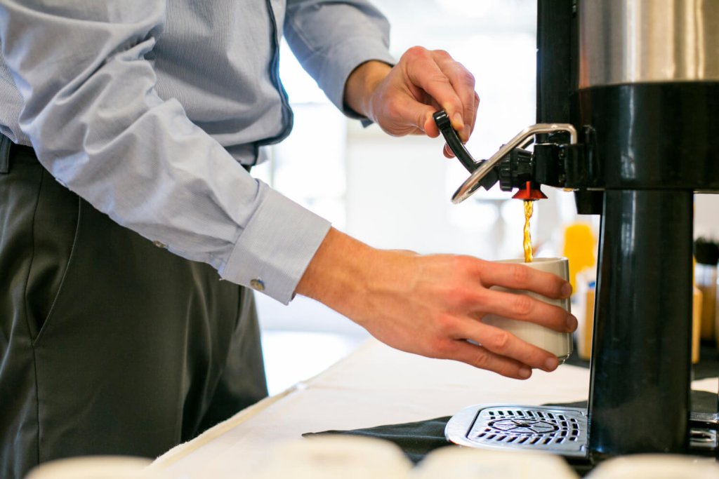 a person getting coffee at their hotel breakfast bar