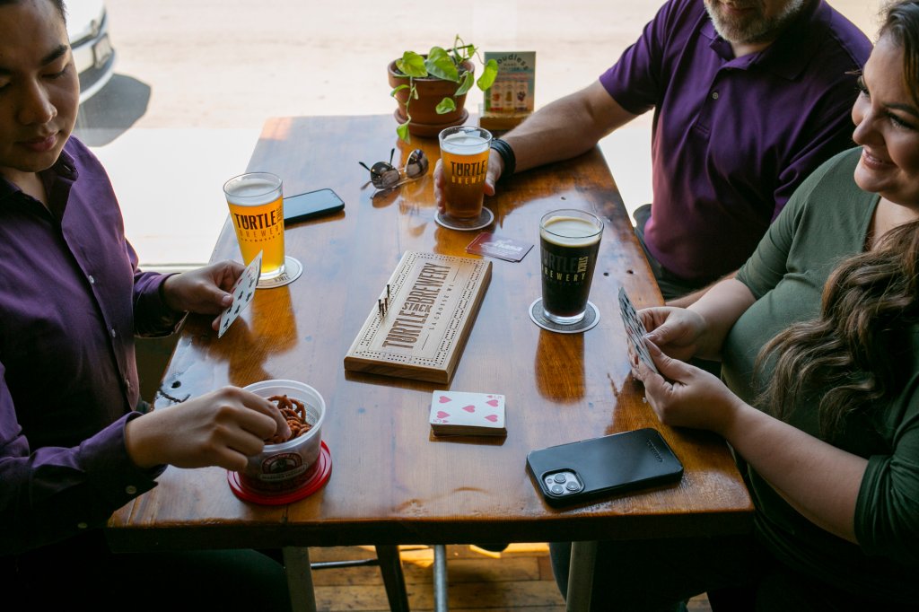 People sitting at a table with beer, snacks and games