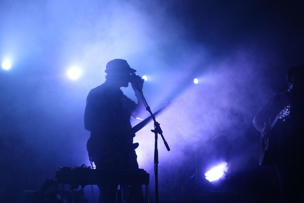 a dramatic shot of a musician performing with lights and smoke behind them
