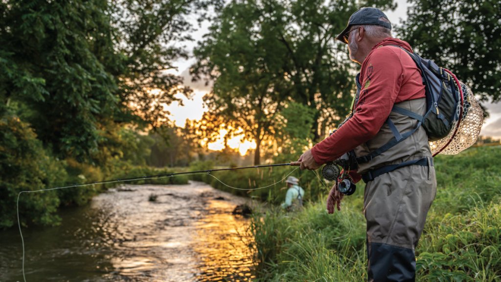A person in a red jacket fishing in the river