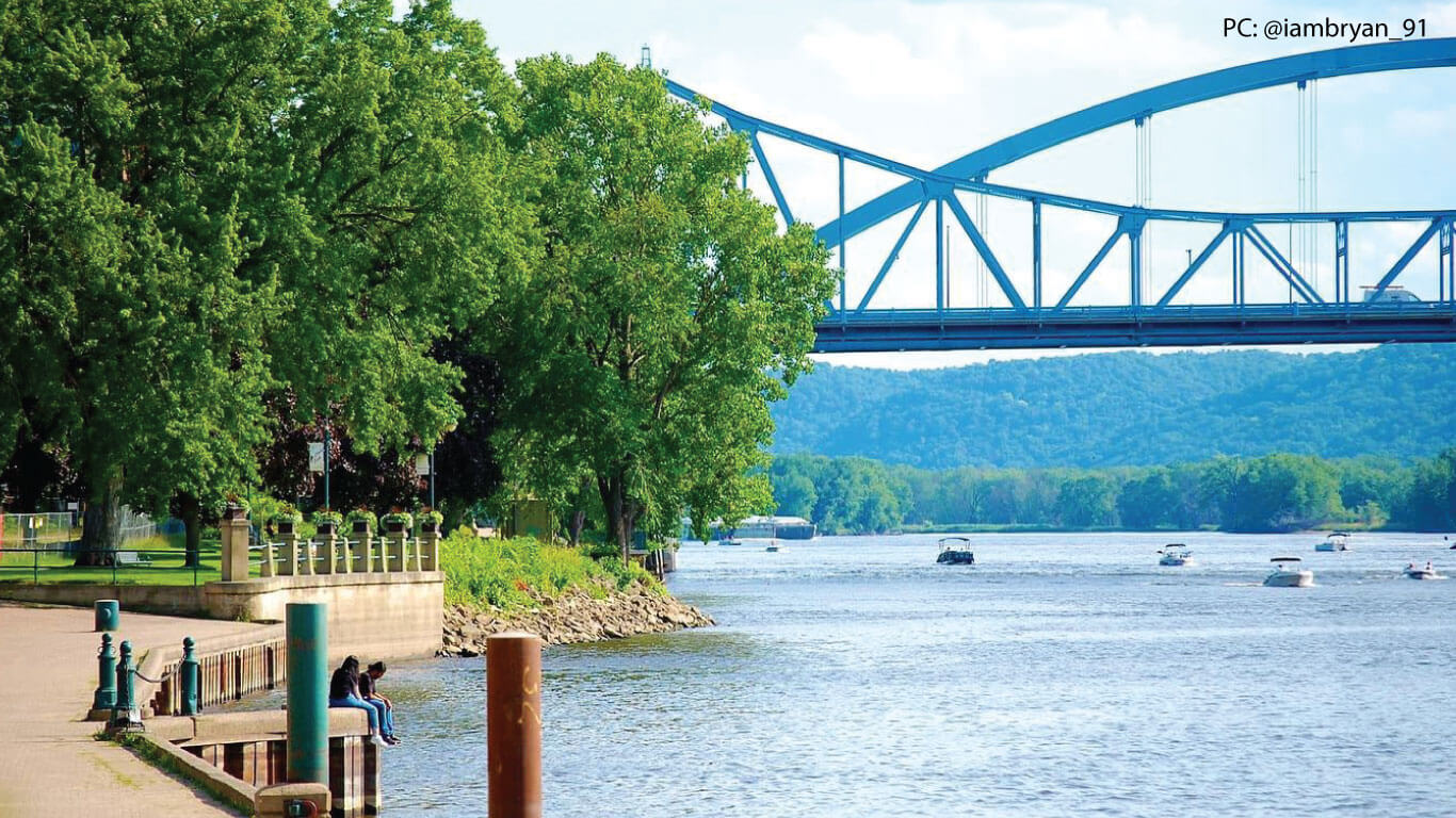 trees to the left and a bridge in the background shot from riverside park