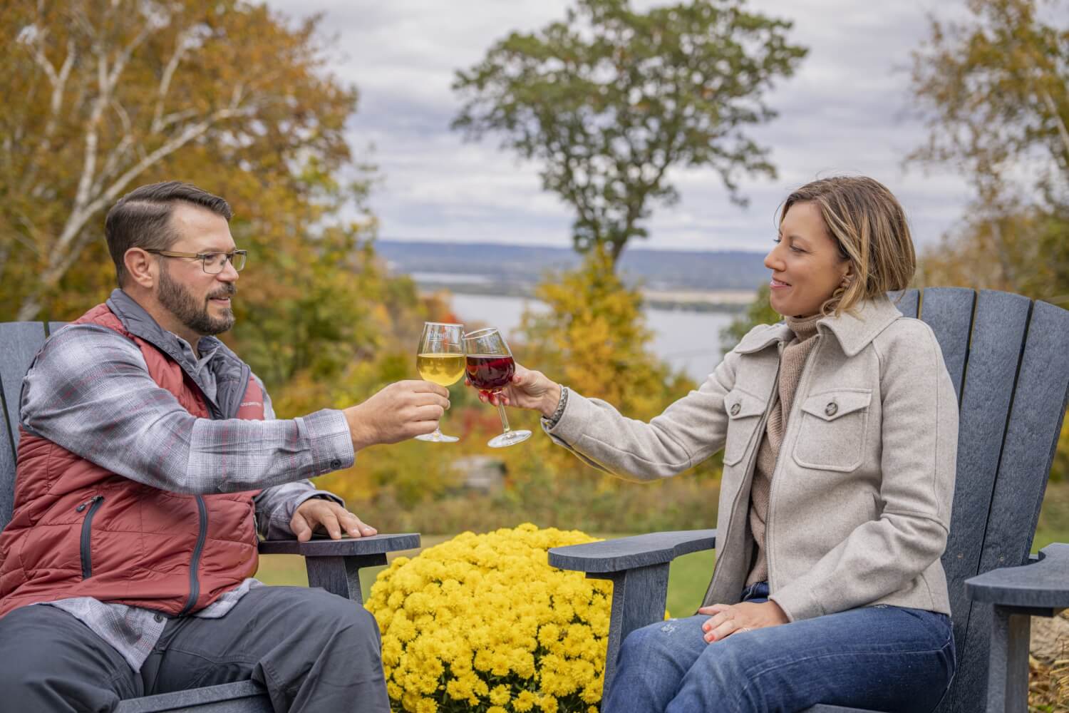 a man and woman sitting on a bench with wine glasses