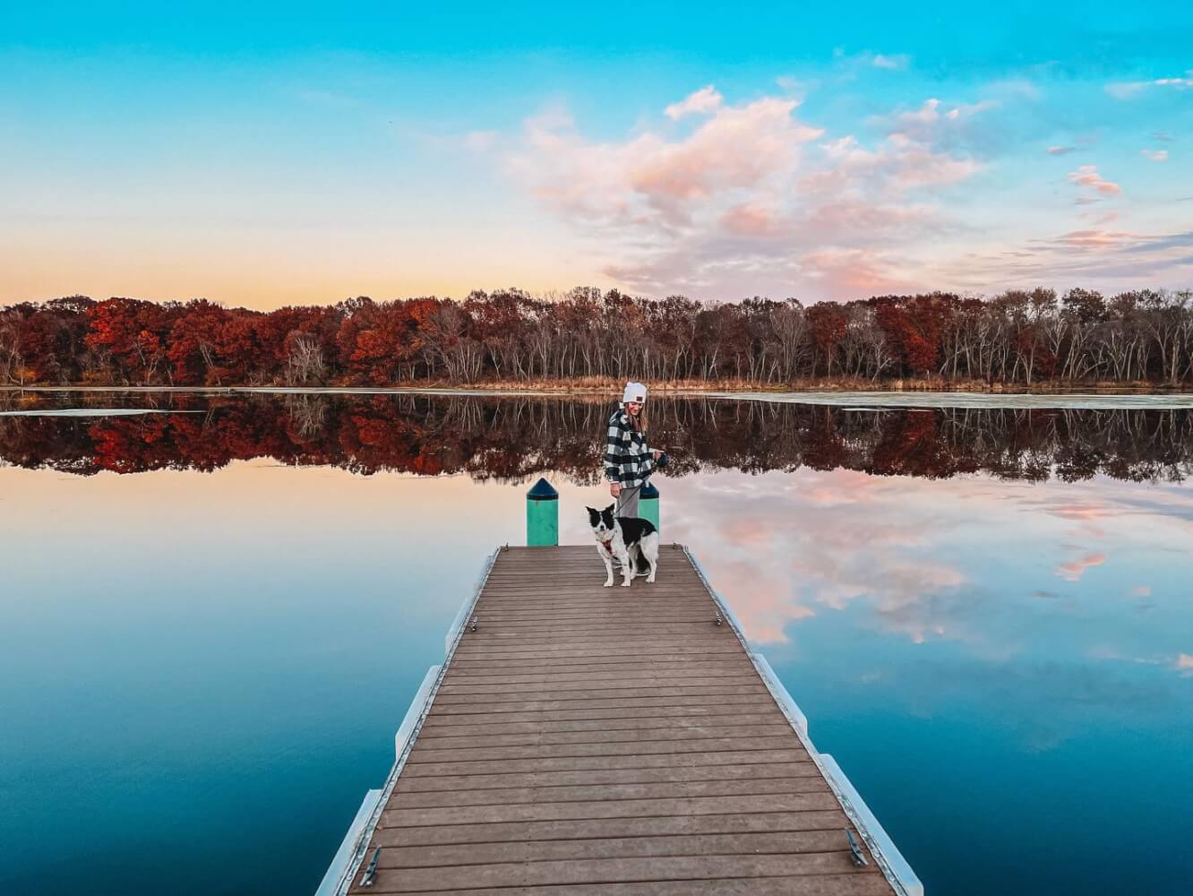 Girl and a dog on a pier overlooking the water during the fall