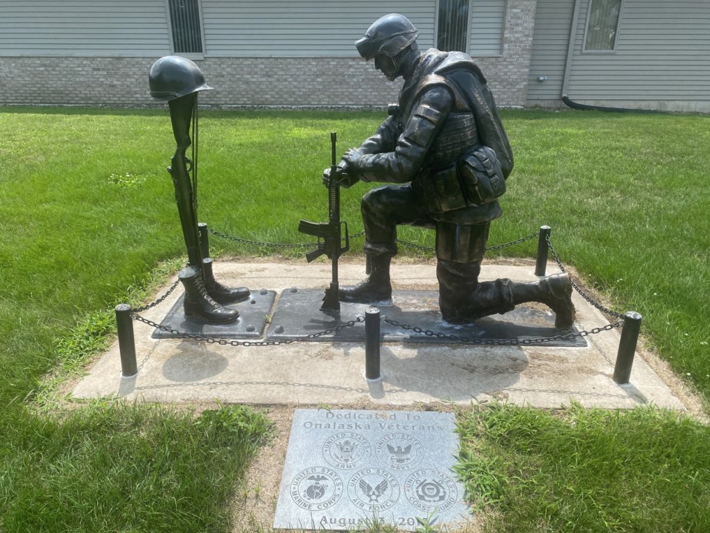 a statue of a soldier kneeling on a platform with a helmet and a gun at