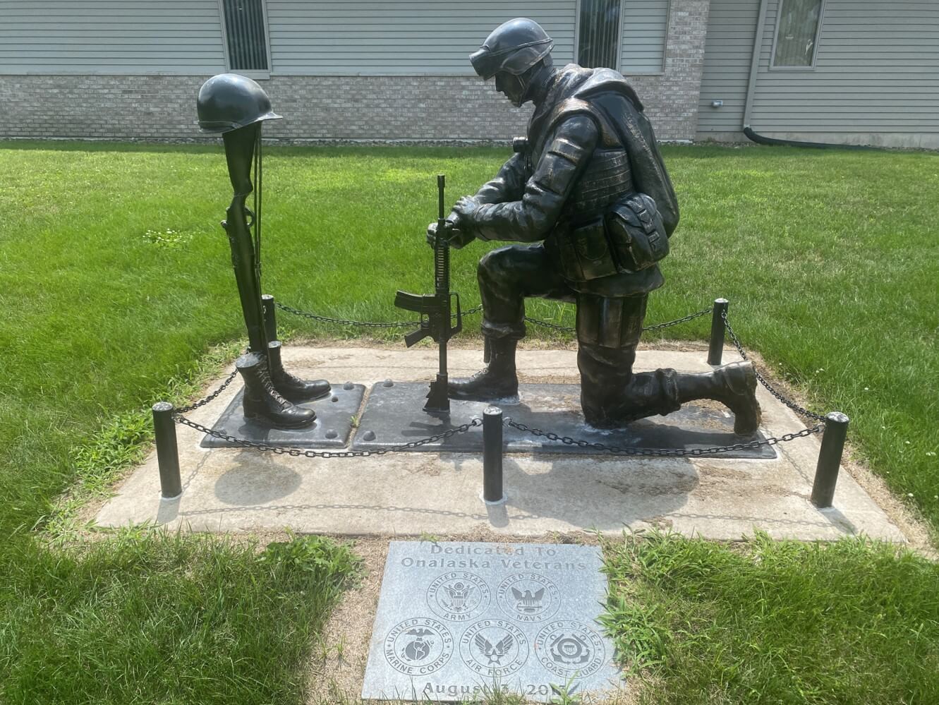 a statue of a soldier kneeling on a platform with a helmet and a gun at