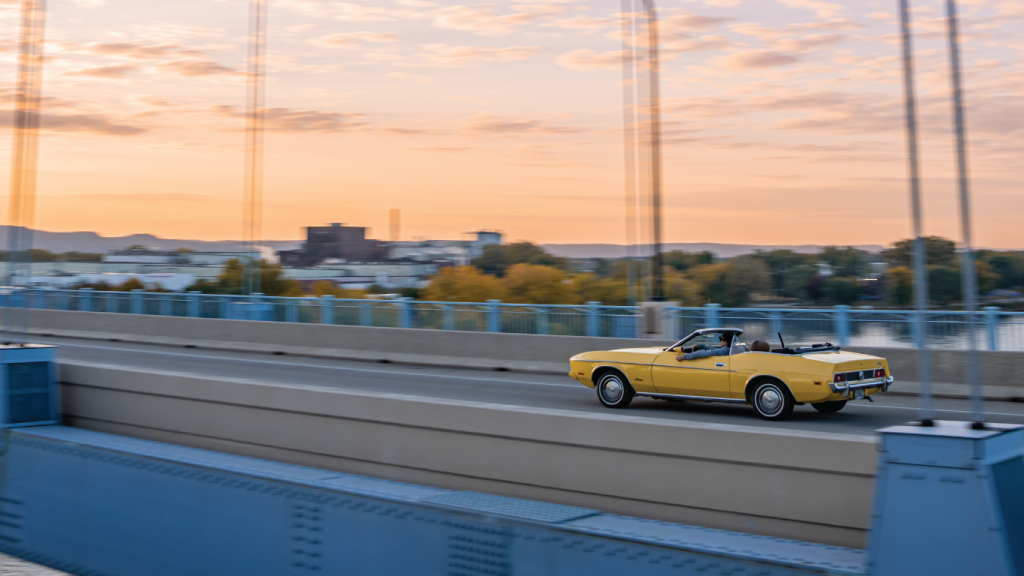 a yellow car driving at sunset