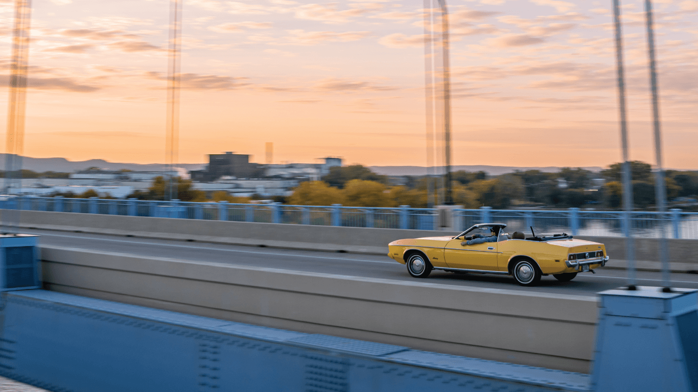 a yellow car driving at sunset