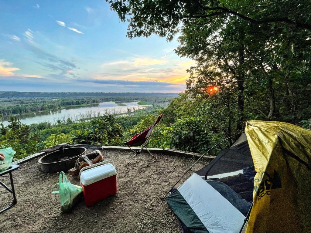 a tent and a fire pit overlooking a river