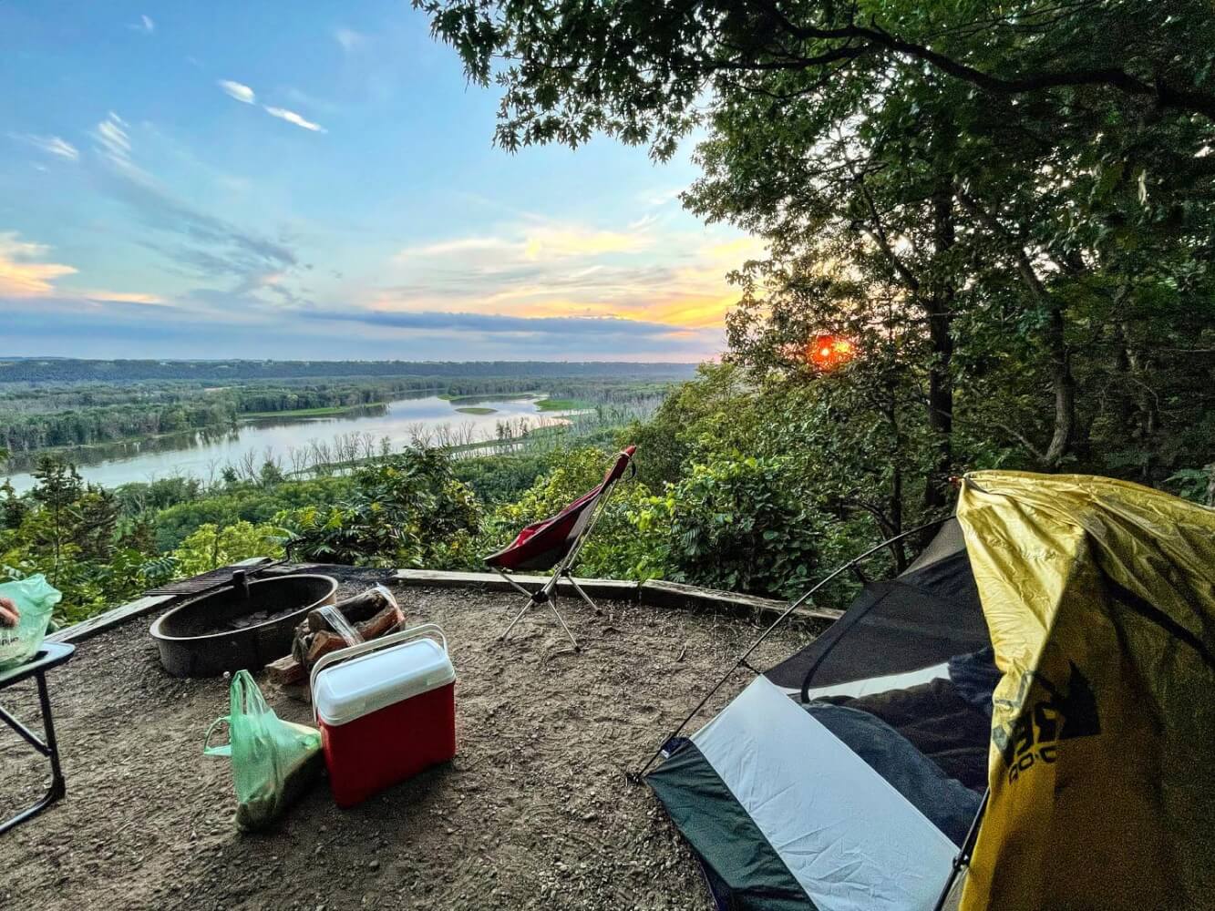 a tent and a fire pit overlooking a river