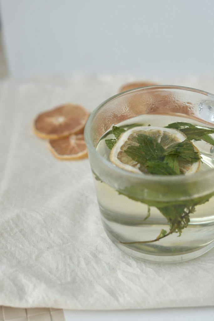a cocktail with a lemon and mint leaf in it