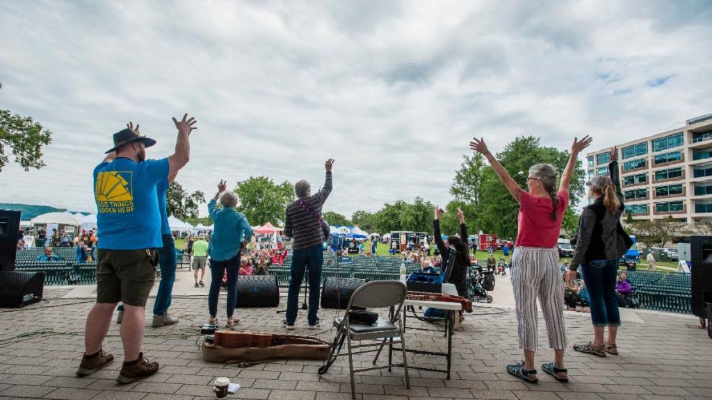 a group of people performing with hands raised to a crowd of people