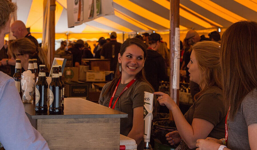 A person smiling under the Beer Wine and Cheese Festival tent