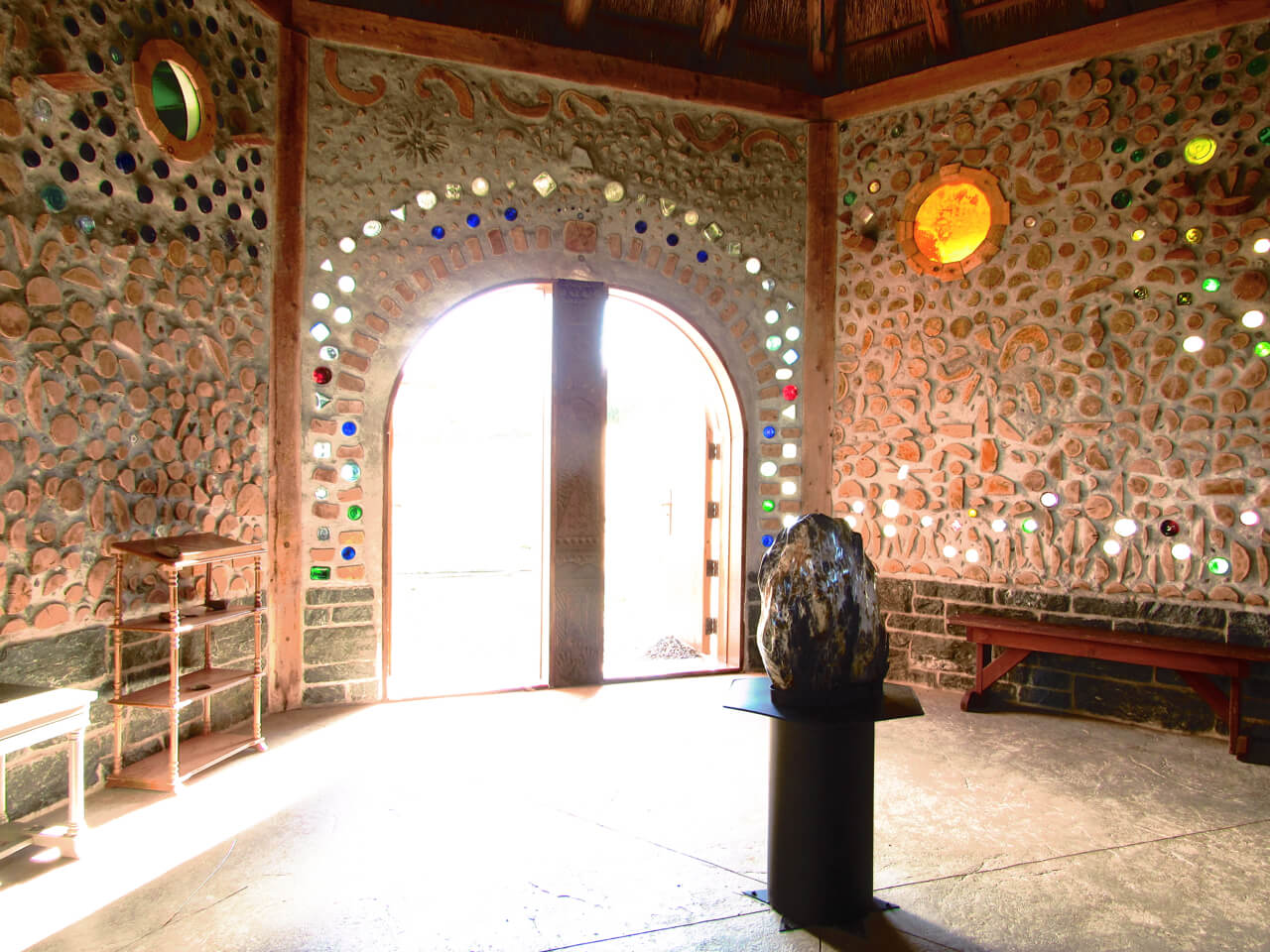 a stone and glass wall with a large rock in the middle