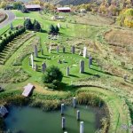 Reasons to Visit Each Season 15 a green field with a pond and a stone structure