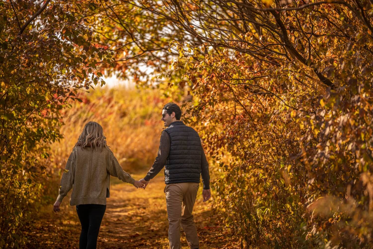 Things to Do 19 A couple holds hands and smile at one another while hiking during peak fall colors in beautiful La Crosse, Wisconsin.