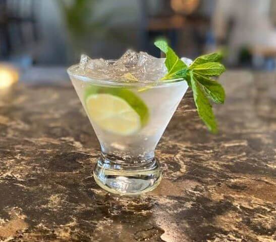 a glass with ice and lime slices on a marble surface