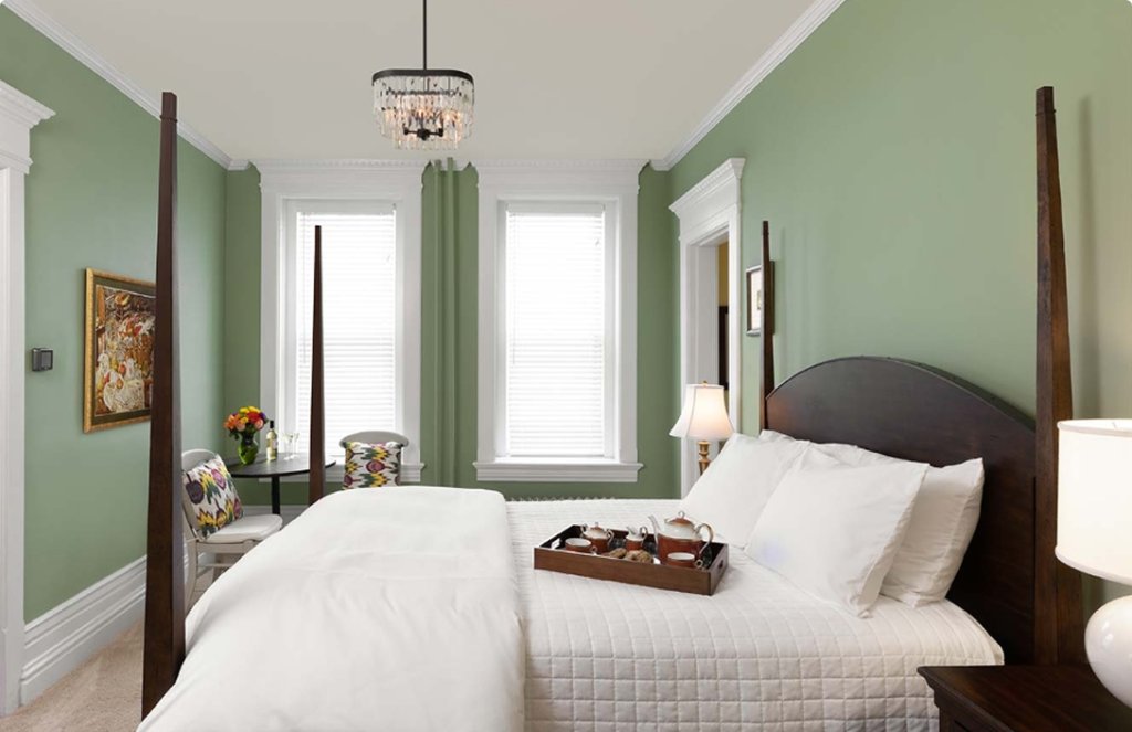 a bedroom with green walls and white bedding