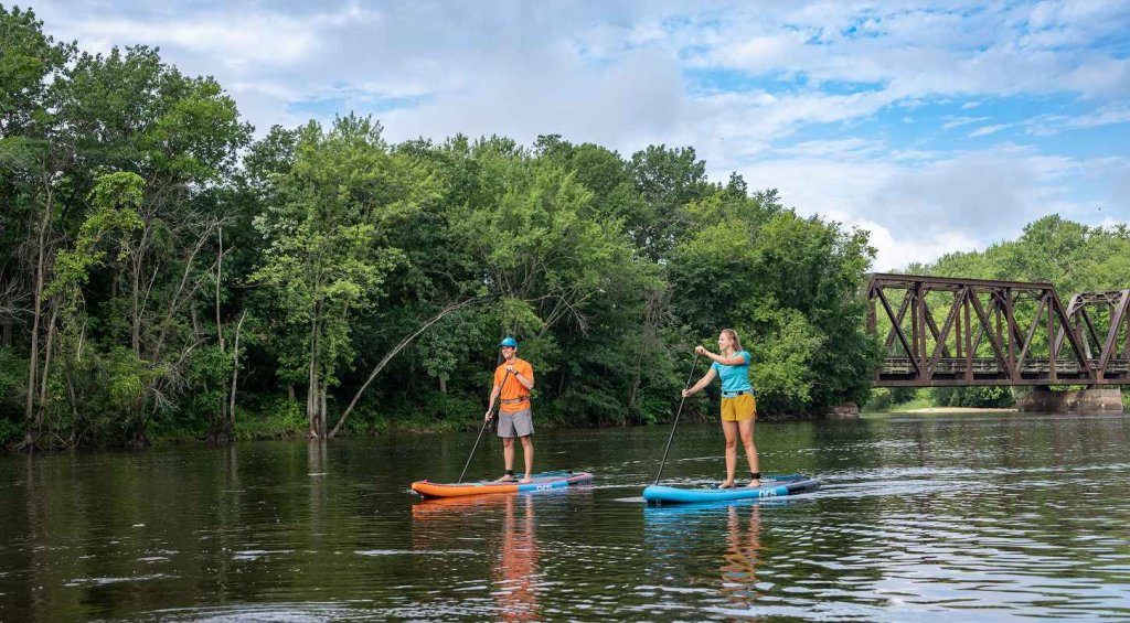a man and woman on paddle boards on a river