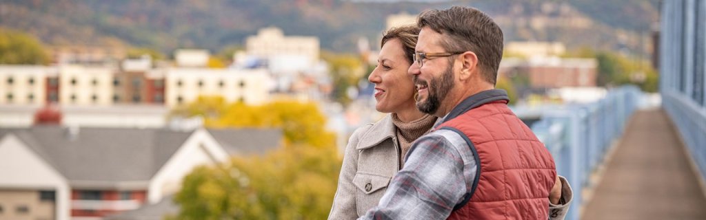 Member Directory 5 A couple smiling while looking off a balcony of downtown la crosse