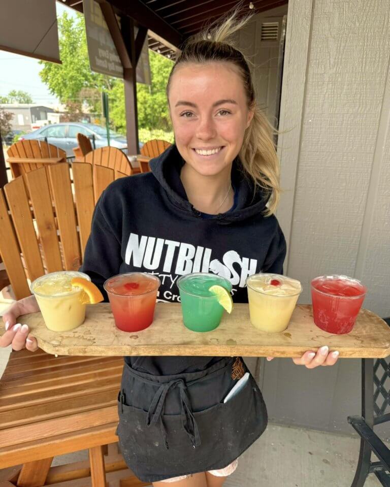 Nutbush employee holding a drink flight at their outdoor patio