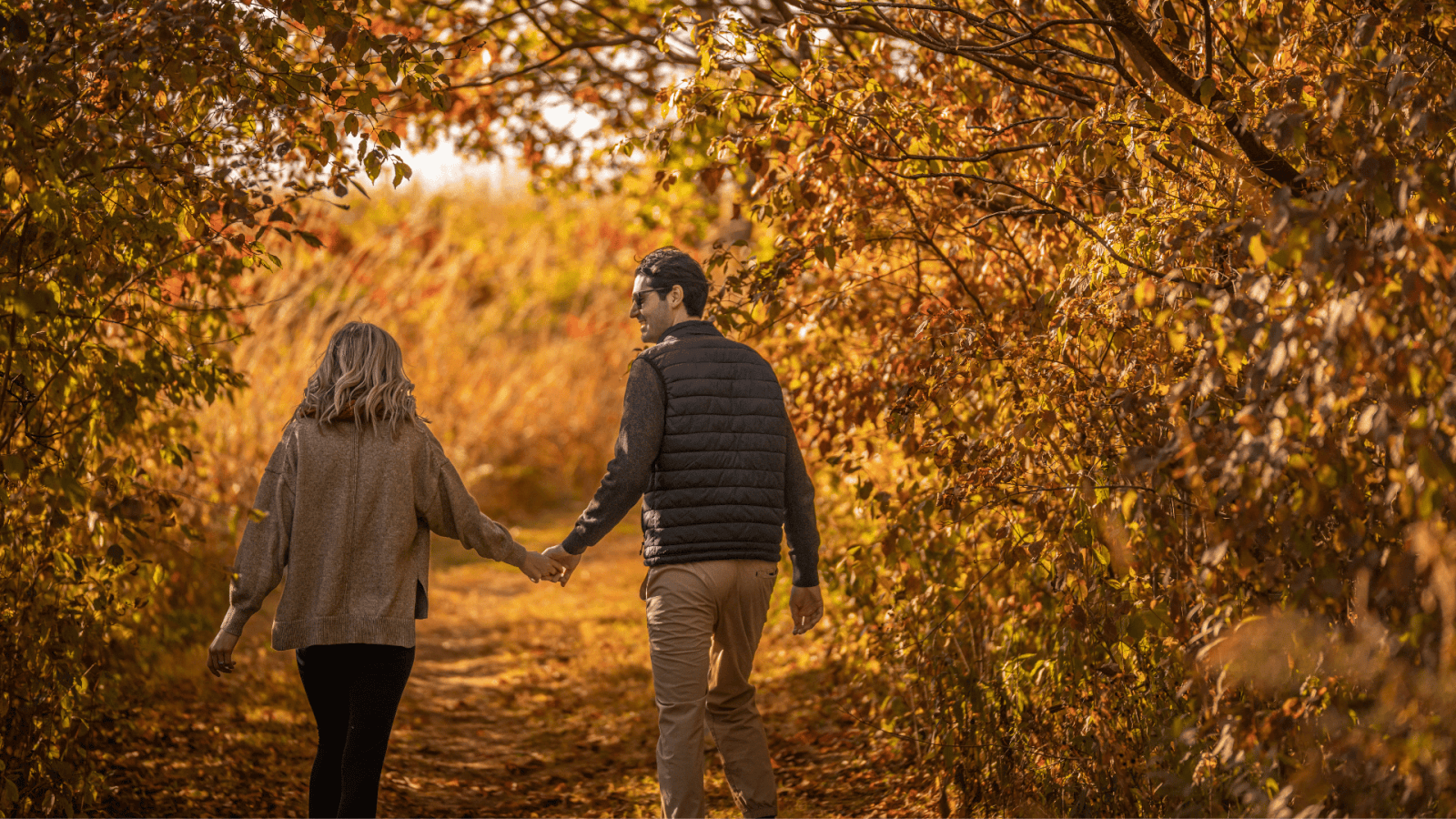 Couple holding hands while hiking in the fall