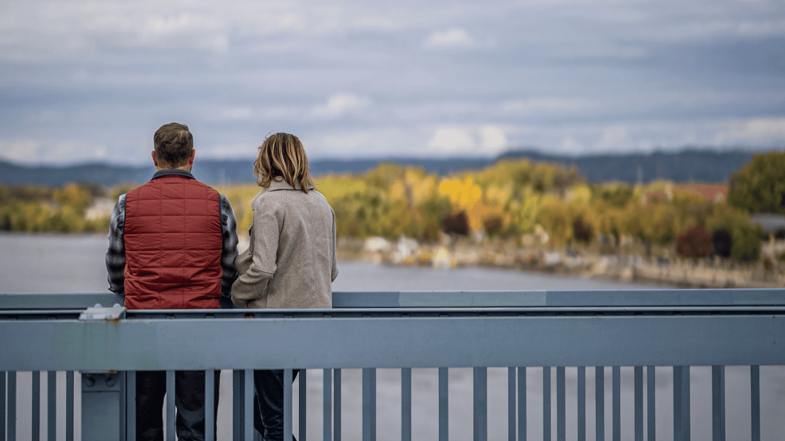 Couple overlooking the Mississippi River in the fall from the Cass Street Bridge