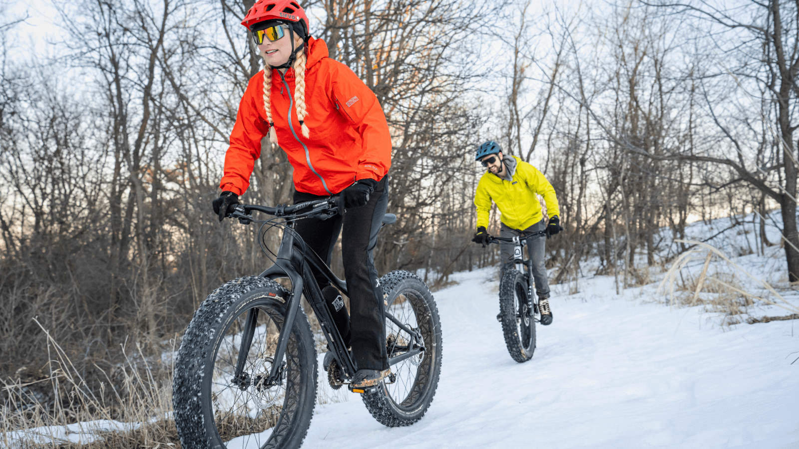 Couple fat tire biking in the woods in winter
