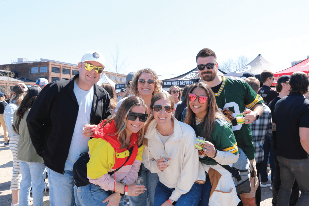 A group of friends celebrating and sampling craft beverages at the between the bluffs beer wine and cheese beverages and bites festival in la crosse wisconsin at the oktoberfest usa grounds in April. 