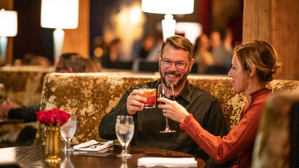 a couple drinking cocktails in a cheers at lovechild restaurant