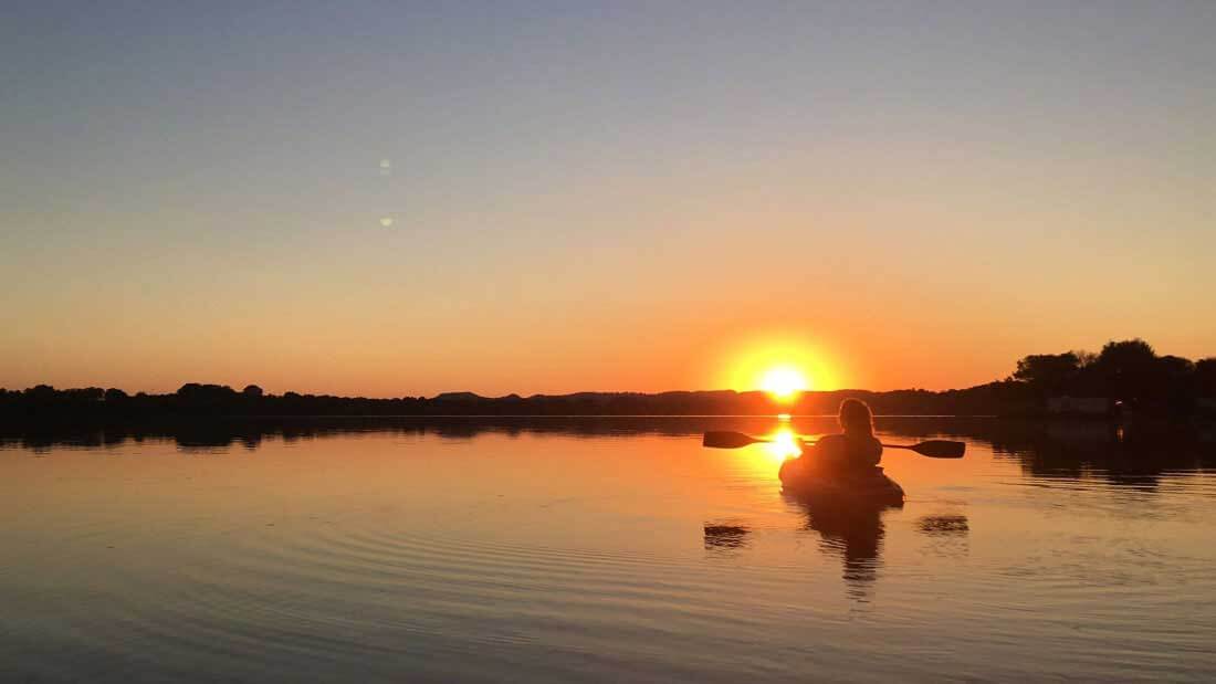 a kayaker paddling at sunset
