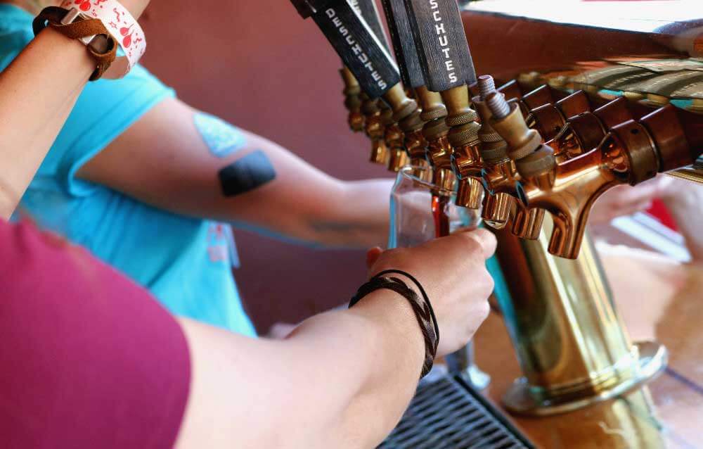 A couple hands fill beer glasses out of the beer tap